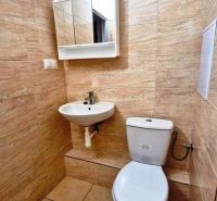 A bathroom in a studio apartment with tiles and a mirrored cabinet above the sink.