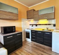 A kitchenette in a studio apartment with a microwave, a cooktop, and a wooden decor floor.
