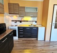 Kitchen unit and appliances in a studio apartment with a wooden decor floor.