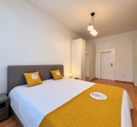 Bedroom in a two-room apartment with a wooden decor floor and white furniture.