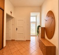 Entrance hallway of a 2-room apartment with tiles and wooden furniture, light streaming through a tall window.