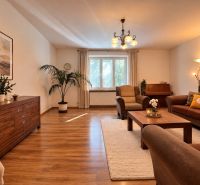 Living room in a two-room apartment with a wooden decor floor and comfortable seating.