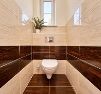 Bathroom in a 2-room apartment with a toilet and dark decor tiles.