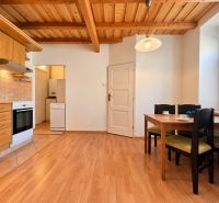A kitchen with a wooden ceiling, a floor with a wooden decor, a table and chairs in a two-room apartment.