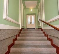 A staircase with green walls, wooden decor, and white doors in a two-room apartment.