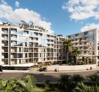 Apartment construction in Phuket with green vegetation, modern architecture, and glass sections.