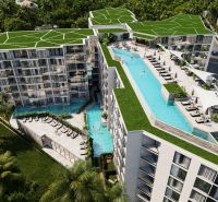 Apartment construction in Phuket with a rooftop pool surrounded by greenery.