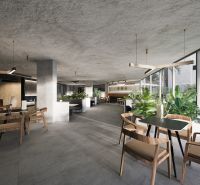 A bright bistro with tables and chairs, indoor plants, apartment construction.