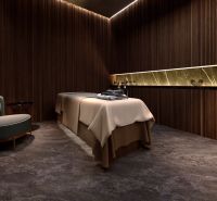 A room with a massage table, a wooden decor floor, and a comfortable armchair. Apartment construction.