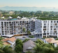 Construction of apartments in Phuket with a view of the sea and surrounding palm trees.