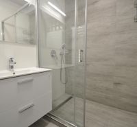 Shower corner with a sink and modern tiles in a 2-room apartment.