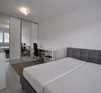 A bright bedroom with a work corner and built-in wardrobes in a 2-room apartment.