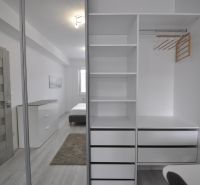 White built-in wardrobe with shelves and mirror in a 2-room apartment.