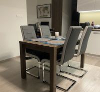 Dining table with four gray chairs in a 2-room apartment, floor with wood decor.