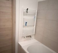 A bathroom with a bathtub and a ladder radiator in a 2-room apartment.