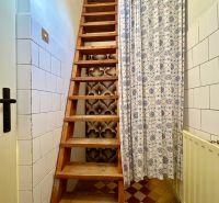 Wooden stairs covered with a curtain in a family house with tiles and cladding.