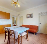 Kitchen in a family house with wooden cabinets, a dining table, and a sofa.