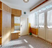 In the family house, there is an entrance hall with wooden furniture and a patterned floor.
