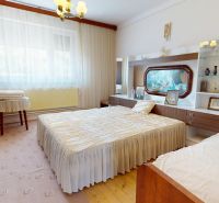 Bedroom in a family house with large windows, beds, and decorative furniture.