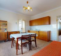 A dining room in a family house with wooden furniture and white tiles on the wall.
