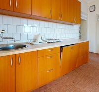 A kitchen in a family house with a wooden decor, equipped with a sink and a cooktop.