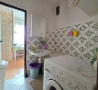 Bathroom in a 2-room apartment with a washing machine, white tiles, and a sink.