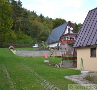 A cottage in Nižná Polianka with two houses, a garden, and a forest in the background.