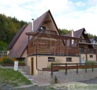 A cottage in Nižná Polianka with wooden details, surrounded by greenery and forest.