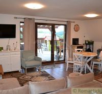 Living room in a cottage with a terrace, dining table, and wooden decor flooring.