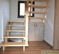 Wooden stairs in a cabin with a wood-patterned floor and a closet underneath them.