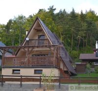 A wooden cabin in Nižná Polianka surrounded by forest, with a wooden balcony and terrace.