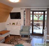 A cottage with a living room, wooden decor flooring, and a view of the terrace with seating.