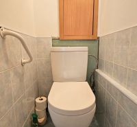 A bathroom with a toilet bowl and a storage cabinet in a studio apartment.
