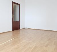 An empty room with white walls and a floor with a wooden decor in a studio apartment.