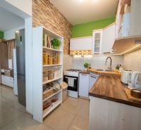 A kitchen in a 2-room apartment with a wooden decor floor and an open shelving cabinet.
