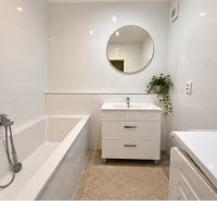 A bathroom with a mirror and a bathtub in a 4-room apartment with decorative tiles.