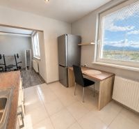 A kitchen with a window and an exercise corner in a 4-room apartment with a wooden decor floor.