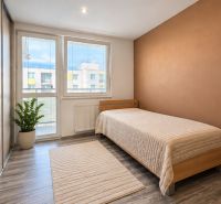 A room of a 4-room apartment with a wooden decor floor and a bed.