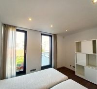 A bedroom in a 4-room apartment with large windows and a wooden decor floor.