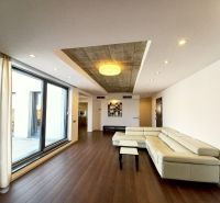 Living room in a 4-room apartment with a glass wall and wooden decor flooring.