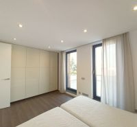 A bedroom in a 4-room apartment with wood-patterned flooring and large windows.