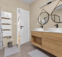 A bathroom with round mirrors and a wooden decor floor in a family house.