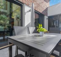 A terrace of a family house with modern furniture and greenery in a flower pot.