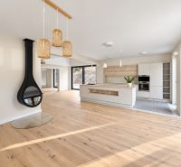 Interior of a family house with a fireplace, kitchen, and wooden decor flooring.