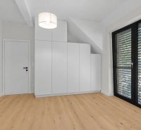 White built-in wardrobe and wooden decor flooring in a family house.