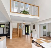 Bright living room with wood-patterned flooring and a staircase in a family house.