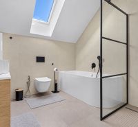 A stylish bathroom with a bathtub, shower, and skylight in a family house.