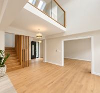 Interior of a family house with an open ceiling, stairs, and floor with wooden decor.