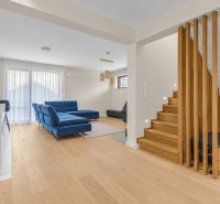 Interior of a family house with a blue sofa, wooden decor flooring, and a staircase.