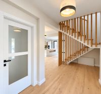 A family house with a wooden decor floor, staircase, and glass doors.